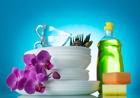 Clean washed dishes and cutlery on a blue background, a branch of an orchidの写真素材