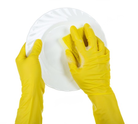 Hands in yellow gloves wash white ceramic plate isolated on white backgroundの写真素材