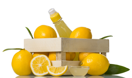 Juicy lemons in a wooden box and juice in a bottle isolated on a white backgroundの写真素材