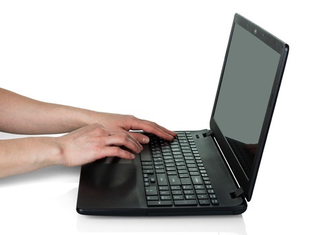 Female hands working behind black laptop isolated on white backgroundの写真素材