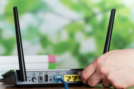 Configuring the router, hands fixing the wires, internet in bright officeの写真素材