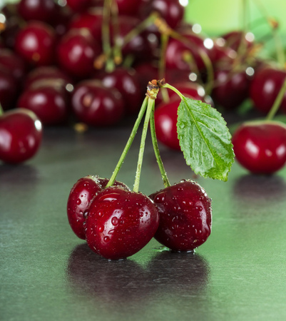 Fresh juicy cherry berries in drops of water on a dark tableの写真素材