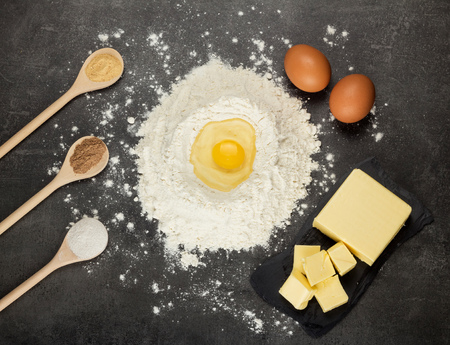 Ingredients for the preparation of aromatic spicy cookies with spices on a dark tableの写真素材