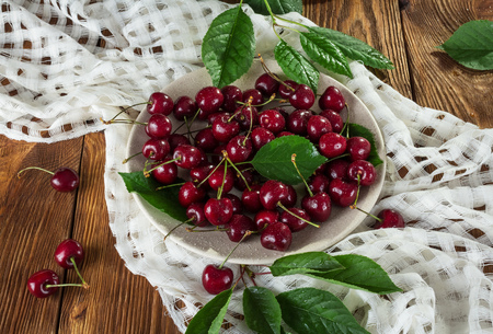 Fresh berries cherries in a bowl with water drops on a white napkinの写真素材
