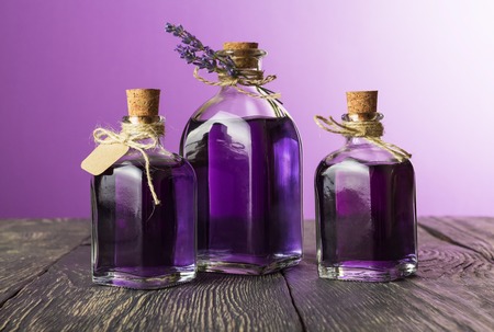 Three glass jars with aromatic tincture of lavender on dark wooden boardsの写真素材