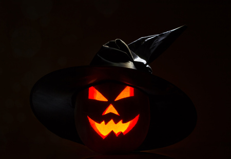 Sinister Jack O lantern Halloween pumpkin with witches hat on black backgroundの写真素材