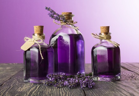 Three bottles with a fragrant tincture of lavender and fresh twigs on a purple backgroundの写真素材