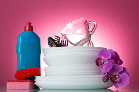 Means for washing and clean white dishes on a pink background decorated with a branch of an orchidの写真素材