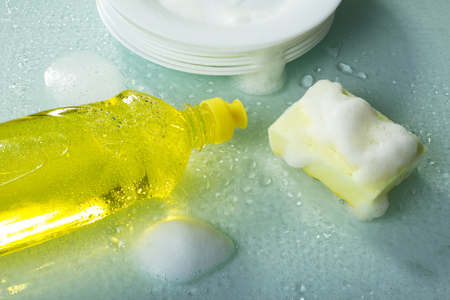 Washing dishes, dish detergent, foam and yellow sponge. Top viewの写真素材