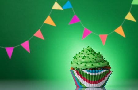 Festive cupcake with cream on a green background decorated with colorful garlandの写真素材