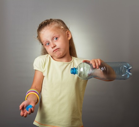 Blonde little beautiful girl surprised by an empty water bottleの写真素材