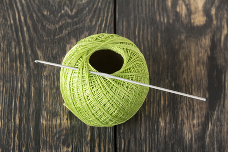 A wool ball of green color and the crochet hook on dark boardsの写真素材