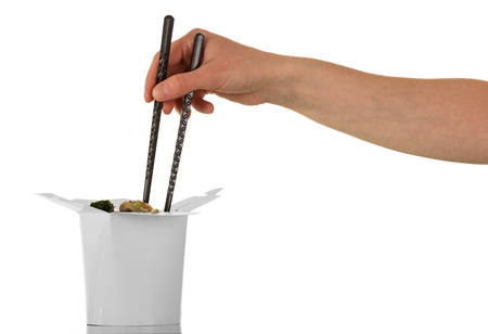 Female hand holding chopsticks pulls the noodles out of the box wok isolated on white backgroundの写真素材