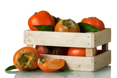 Fresh ripe persimmon in a wooden box and cut pieces isolated on white backgroundの写真素材