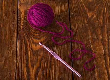 Skein of purple wool yarn and crochet hook on dark boardsの写真素材
