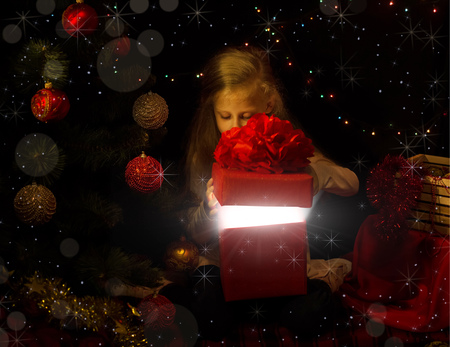 The magic of Christmas. The little girl in the new year location looks in a gift boxの写真素材