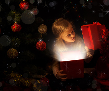 The magic of Christmas. The little girl in the new year location looks in a gift boxの写真素材