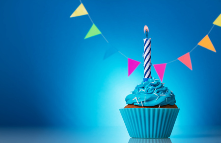 Cupcake birthday with candle beautiful on a bright blue backgroundの写真素材
