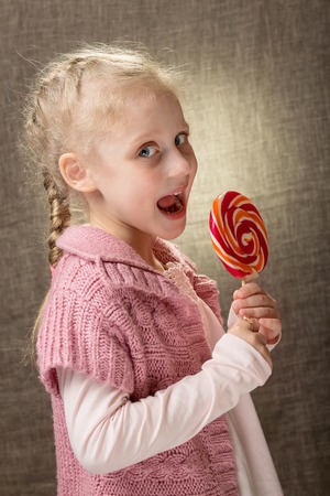 Cute beautiful blonde little girl holding a lollipop. Bright portraitの写真素材