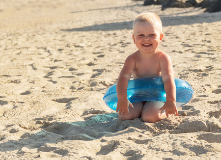 Happy little boy on a sunny beach in a circle for swimmingの写真素材