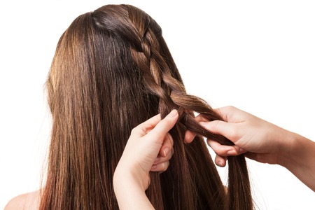 The hands of the stylist weaves long, silky hair, isolated on white backgroundの写真素材