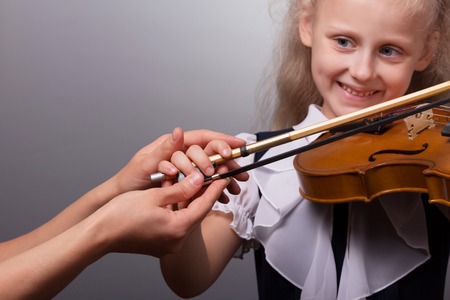 Teacher shows the correct way to hold the bow a little girl studying to play the violinの写真素材
