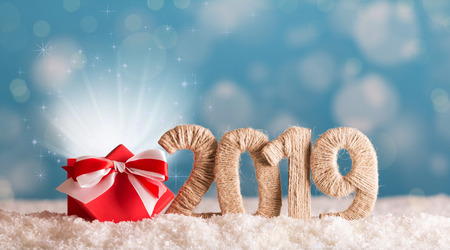 Inscription 2019 new year and red box of magic in the snow on background with bokeh effectの写真素材