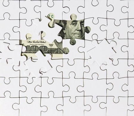 Background of white puzzle in the center of which the banknote in 100 dollarsの写真素材