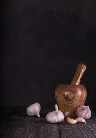 Composition of garlic and mortar to prepare the spices on dark backgroundの写真素材