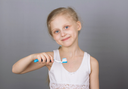 ?oncept of a healthy lifestyle. Caring for children's teeth. Girl brushing her teeth over grey backgroundの写真素材
