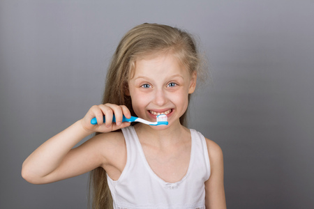 ?oncept of a healthy lifestyle. Caring for children's teeth. Girl brushing her teeth over grey backgroundの写真素材