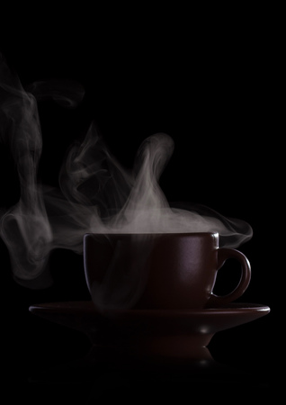 Cup of fragrant hot drink with steam isolated on black backgroundの写真素材