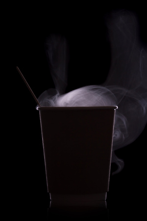 Paper eco cups for hot drinks. Silhouette with steam isolated on black backgroundの写真素材