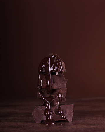 Melted chocolate icing dripping down the large chunks of chocolate on a dark backgroundの写真素材