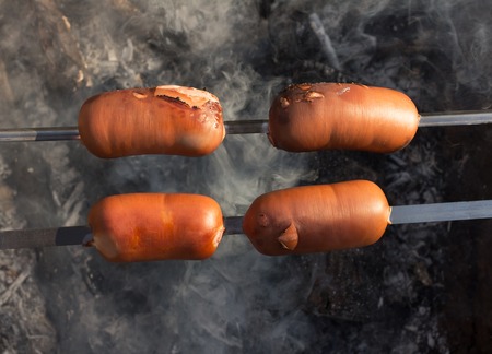 Picnic. Spicy, delicious with golden brown sausages roasted on the campfire outdoorsの写真素材