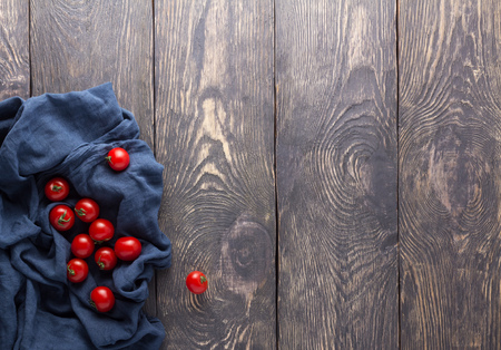 Top view. Fresh juicy cherry tomato in a blue towel on the kitchen tableの写真素材