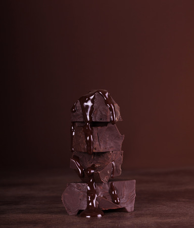 Chunks of chocolate folded pyramid of molten chocolate over dark backgroundの写真素材