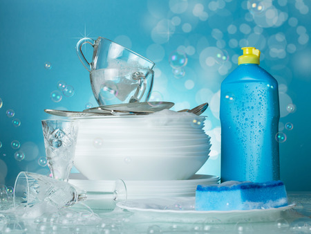 Clean washed dishes, dishwashing and soap bubbles on blue backgroundの写真素材