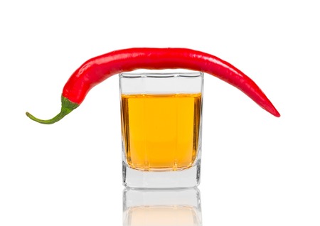 Glass of vodka with pepper and spicy red pepper isolated on white backgroundの写真素材