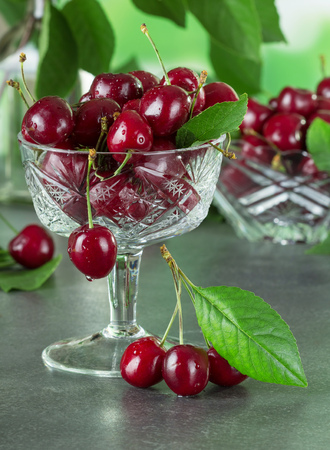 Fresh juicy berries cherries in a crystal vase on the table in the water dropletsの写真素材
