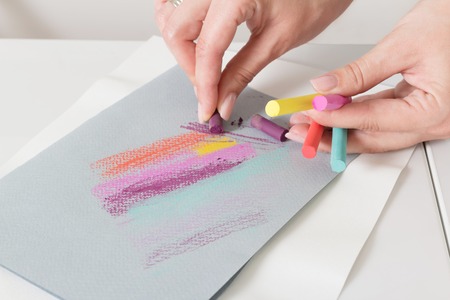 Artist's hand draw chalk pastels on gray paper abstract lines