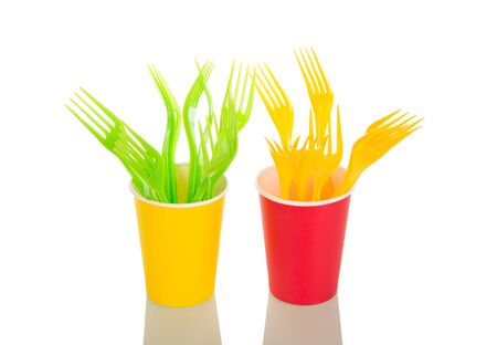 Yellow and light green forks are in colorful plastic cups isolated on white backgroundの写真素材