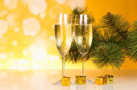 Champagne, Christmas pine twig and small gifts, on bright yellow backgroundの写真素材