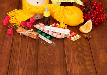 Berries of kalina, spices for tea with lemon and tablets from colds, against the background of wooden tableの写真素材