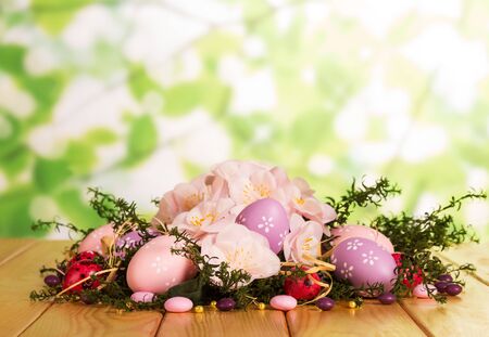 Colored Easter eggs, sweets, herbs, flowers and ribbon on abstract green background.の写真素材