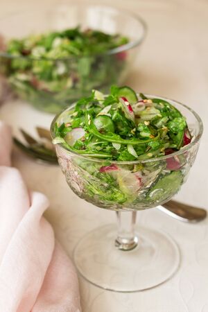 Fresh spring salad in glass bowl on beige tableclothの写真素材