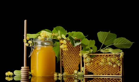 Pot with honey, wooden frame with honeycomb isolated on black backgroundの写真素材