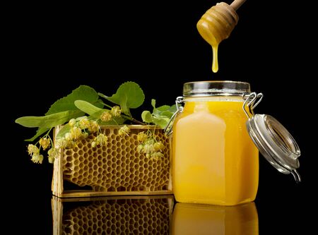 Wooden stirrer for honey and honeycombs, isolated on black backgroundの写真素材