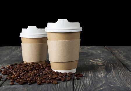 Containers with lid for hot coffee to takeaway on gray wooden table, next to scattered grainの写真素材