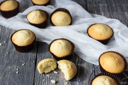 Large number of freshly baked cupcakes and easy white fabric on grey wood surfaceの写真素材